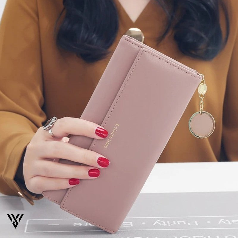 LeisureTime Pendant Wallet in pink, lifestyle image of a woman showing the stylish, multifunctional wallet above a table - VAYOME.